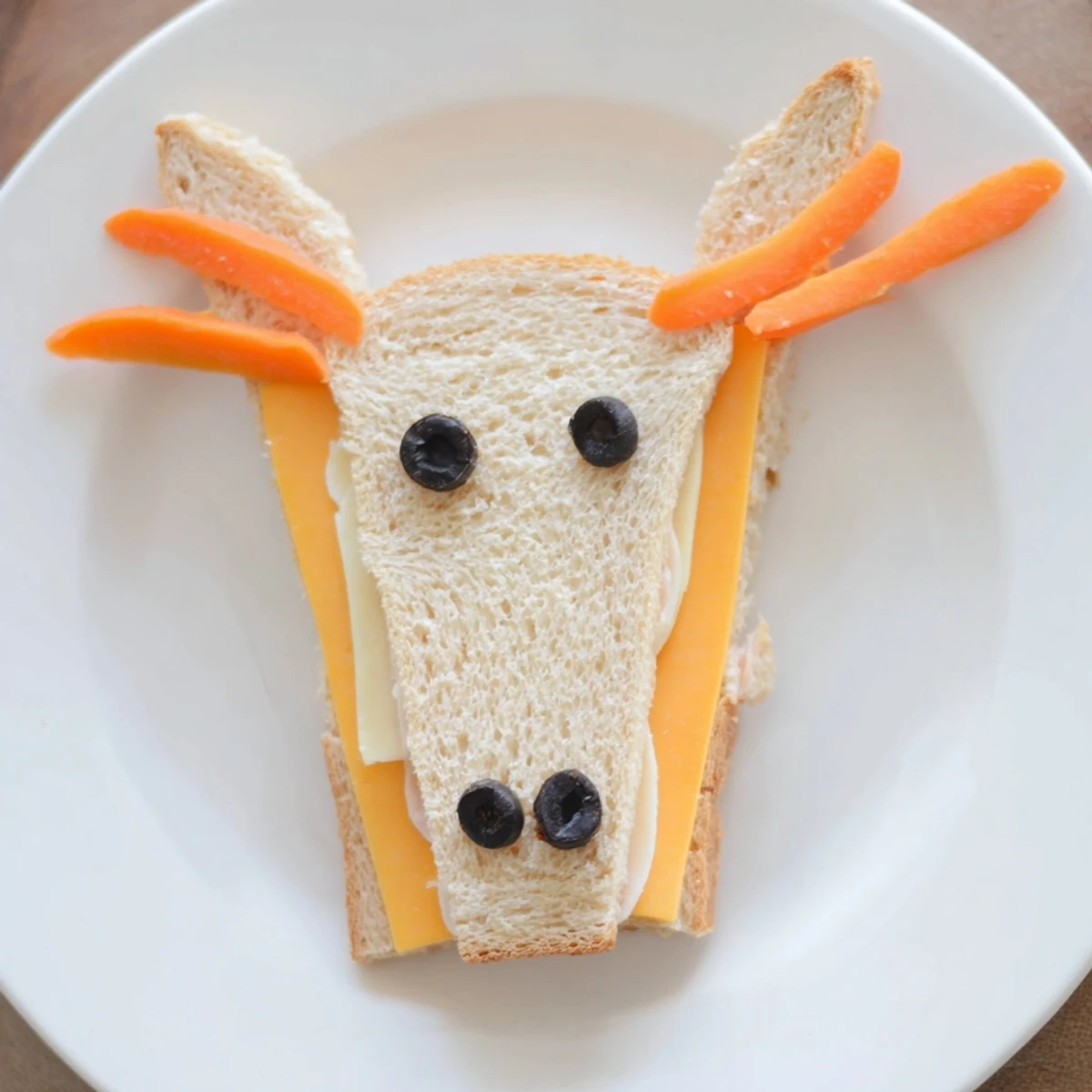 Vibrant Horse Head Sandwich cutouts with black olive eyes and carrot manes for a fun kid's lunch.