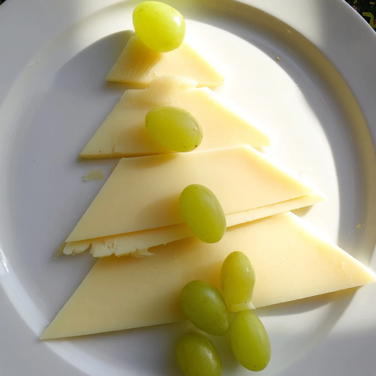 Festive Tannenbaum Border cheese board featuring triangular cheese “trees” and vibrant green grapes.