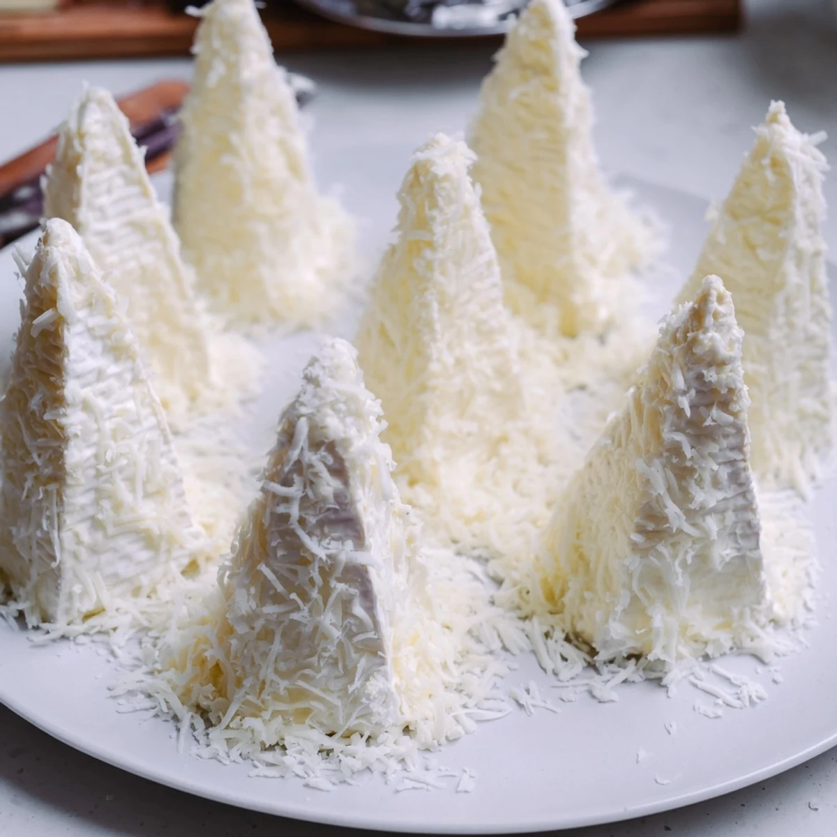 This easy Snowcapped Range appetizer showcases Brie triangles dusted with grated Parmesan.