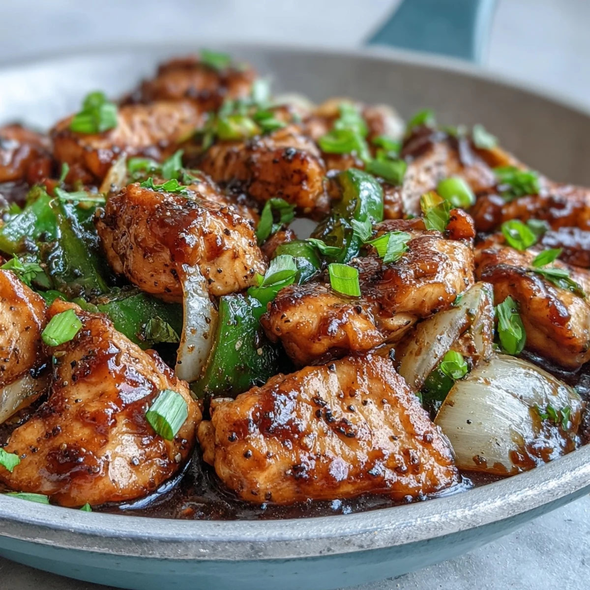 Juicy chicken pieces and crisp green peppers coated in glossy, bold black pepper sauce, ready to serve over steamed rice.