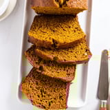 Moist pumpkin bread loaf studded with walnuts and chocolate chips, drizzled with a light glaze.