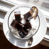 Sweetened cream cascades over chilled coffee jelly cubes in a serving glass, offering a light and elegant treat for coffee lovers.