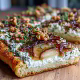 Close-up of Goat Cheese & Pear Flatbread with Hot Honey, showing creamy cheese melting with sliced pears and drizzled chili honey.
