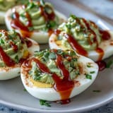 Vibrant deviled eggs with avocado filling and zesty Sriracha kick, garnished with cilantro and paprika.