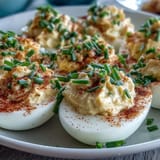 Classic Deviled Eggs with Paprika and Chives: A platter of elegant deviled eggs topped with vibrant paprika and chopped chives, perfect for parties.