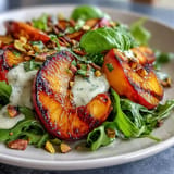 Vibrant grilled peach and burrata salad, drizzled with honey balsamic dressing for freshness.