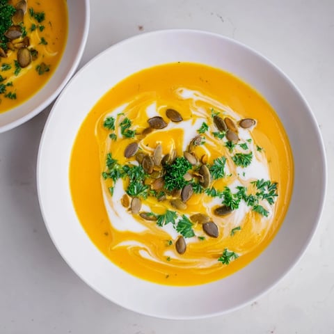 Creamy, vibrant butternut squash soup, garnished with fresh herbs, offering a taste of autumn warmth.