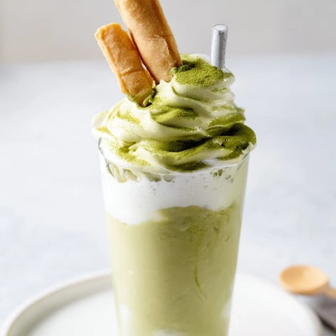 Sugar-Free White Chocolate Candy Cane Iced Matcha layered in a glass, with whipped cream and crushed candy canes.