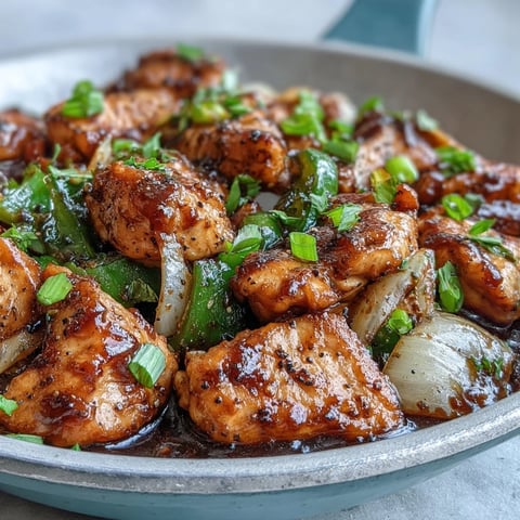 Juicy chicken pieces and crisp green peppers coated in glossy, bold black pepper sauce, ready to serve over steamed rice.