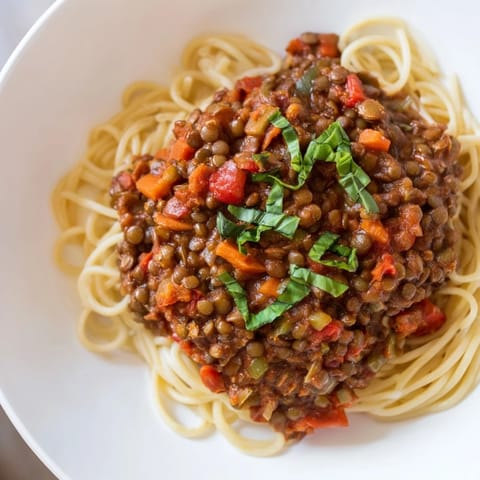 Close-up of bubbling Hearty Lentil Bolognese, a plant-based sauce with visible vegetables, perfect for pasta night.
