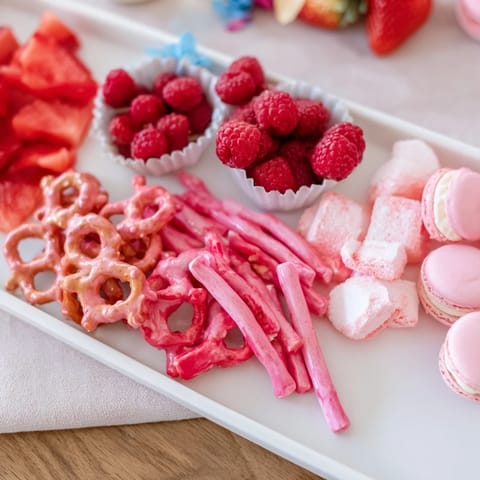 Colorful pink and blue baby reveal snack board bursting with fresh fruits, perfect for a party.