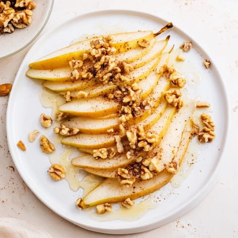 Plate of juicy pear slices glistening with a honey drizzle ready to enjoy as a sweet snack.