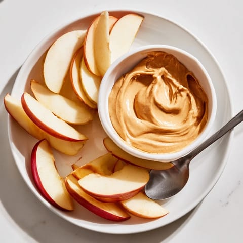 Freshly sliced apples arranged beside a small bowl of homemade peanut butter dip.