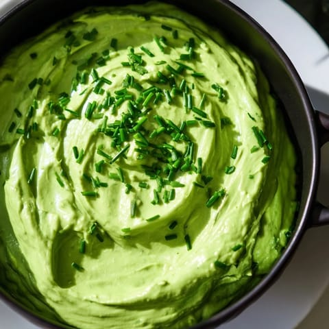 Vibrant Witch's Brew Cauldron appetizer, a spooky green dip, encircled by dark, smoky-looking garnishes.