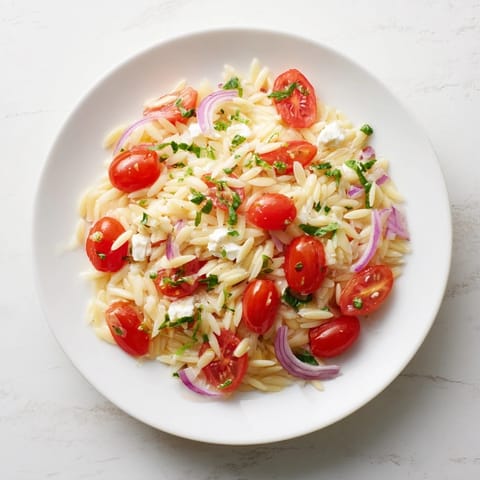 Close-up of Tomato Feta Orzo, showcasing bright red tomatoes and creamy, crumbled feta.
