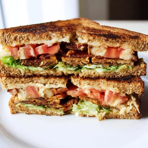Vegan BLT grilled cheese on toasted sourdough, stacked with crispy tempeh bacon and ripe tomato.  