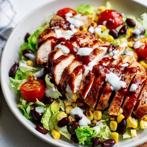 A hearty BBQ Chicken Salad features vibrant cherry tomatoes and red onion for a fresh, smoky flavor.