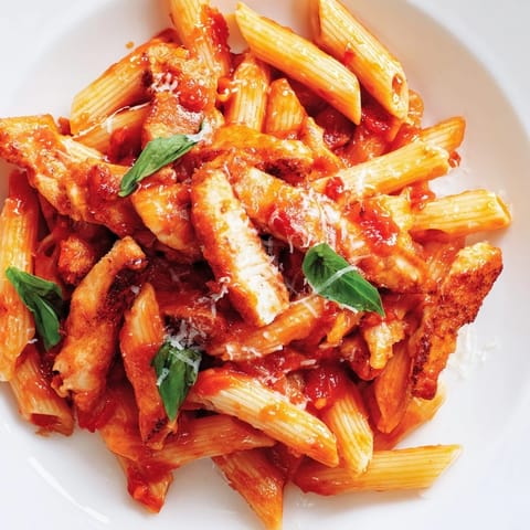 Spicy Tomato Chicken Pasta is served hot in a rustic skillet, showcasing the zesty chili-infused tomato sauce and tender penne.  