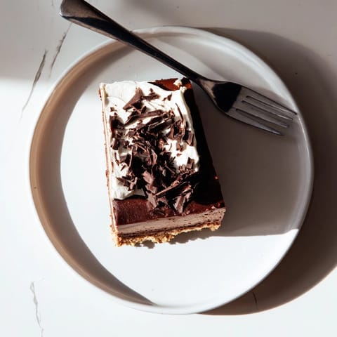 A slice of Lighter Chocolate Chocolate Cottage Cheese Cheesecake sits on a white plate with fresh berries nearby.