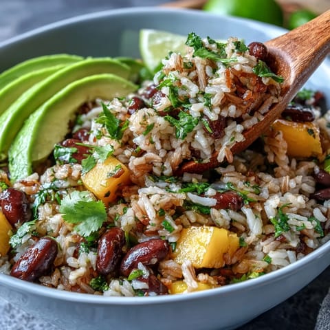 Vibrant mango and black bean brown rice fiesta bowl with fresh avocado, tomatoes, and zesty lime dressing, perfect for a healthy vegetarian meal.  