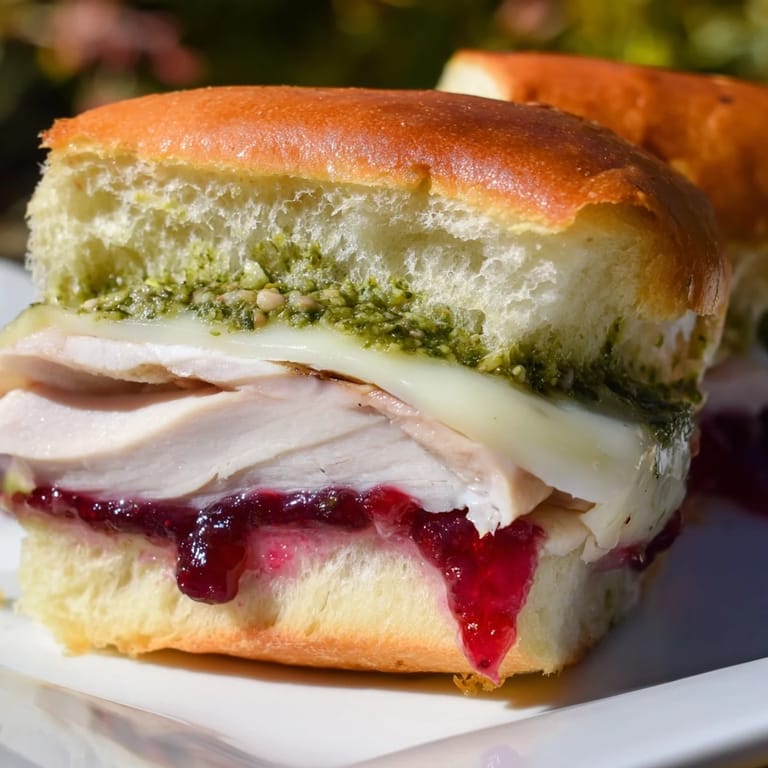 Mouthwatering close-up of a Pesto Cranberry Turkey Grilled Cheese Melt, oozing delicious melted cheese and cranberry sauce.