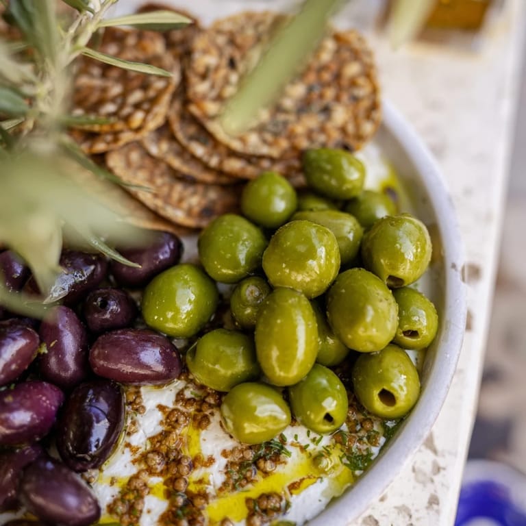 Close-up of the delicious cobblestone courtyard, showcasing assorted olives nestled between round crackers, ready to serve.