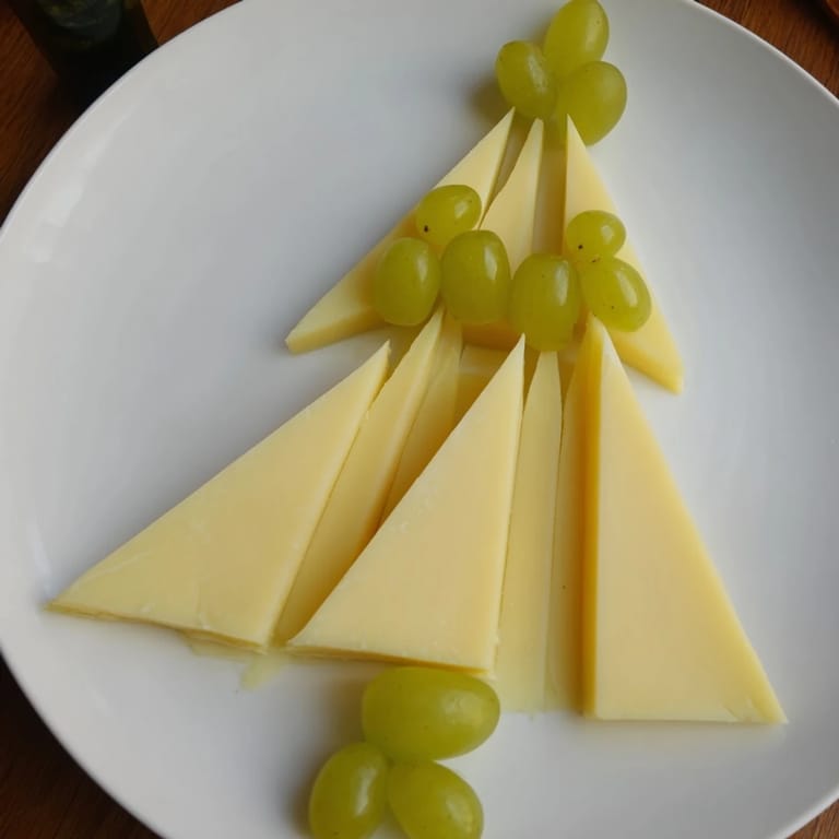 A beautiful Tannenbaum Border cheese appetizer with Gouda trees, grapes, and ready to serve for the holidays.