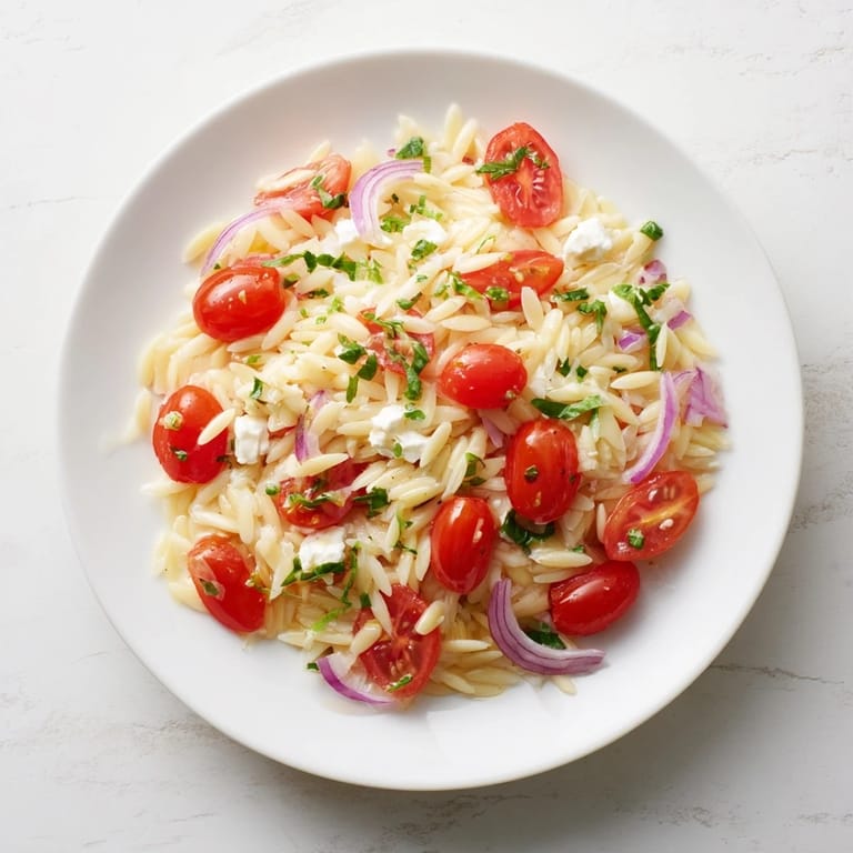 Close-up of Tomato Feta Orzo, showcasing bright red tomatoes and creamy, crumbled feta.