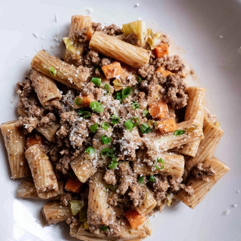 Close-up of creamy, flavorful Chaos Cooking Kimchi Ragu Pasta, garnished with scallions and grated Parmesan cheese.