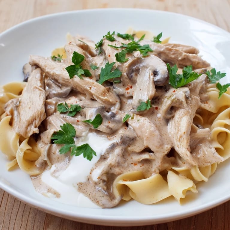 Comforting Chicken and Mushroom Stroganoff plated for a family dinner, garnished with parsley and steam rising.