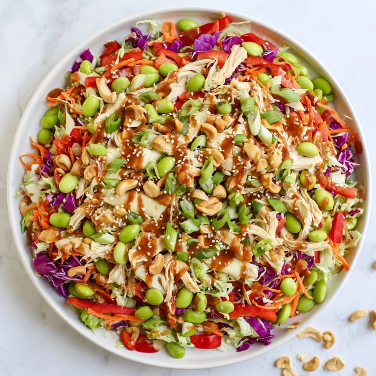 Colorful Edamame Crunch Chicken Salad with red bell pepper and green onions, ready to serve alongside a glass of iced green tea.